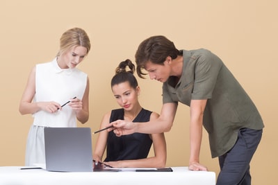 男人一边教女人一边指着灰色的笔记本电脑
